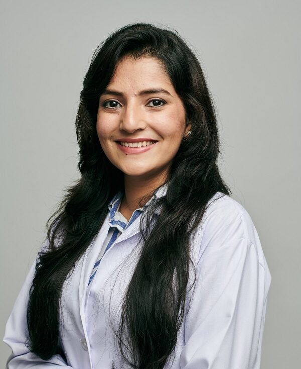 Female dentist Dr. Saumya Jain smiling in professional white coat at dental clinic