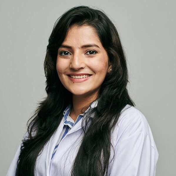 Female dentist Dr. Saumya Jain smiling in professional white coat at dental clinic