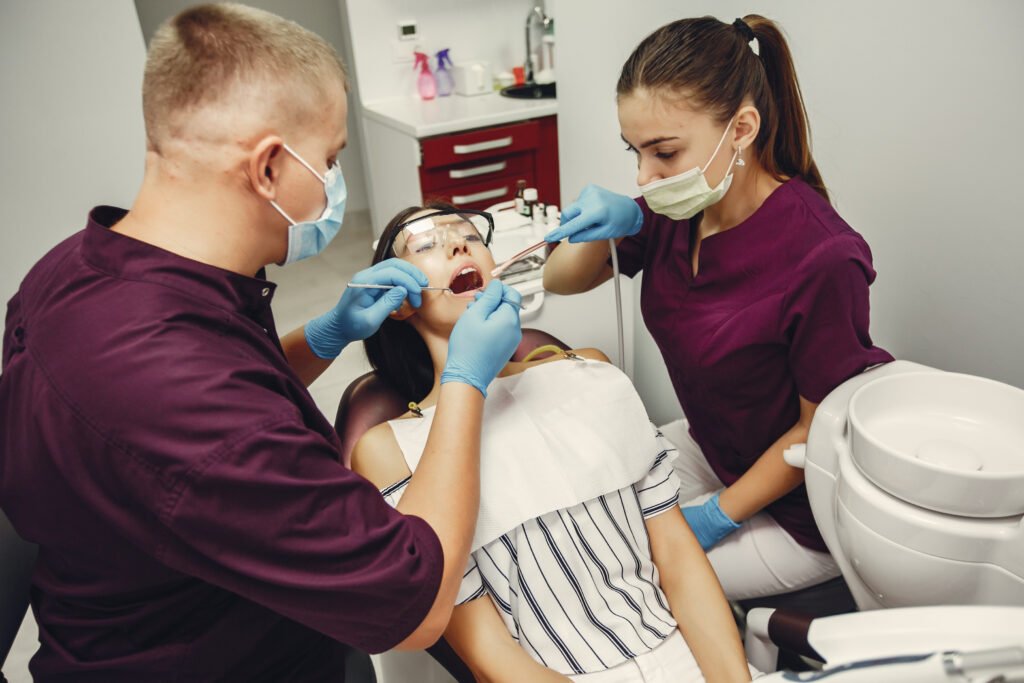 Dentist and dental assistant performing dental treatment on patient in clinic