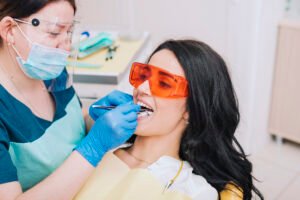 Dentist performing dental treatment using safety glasses and modern dental tools