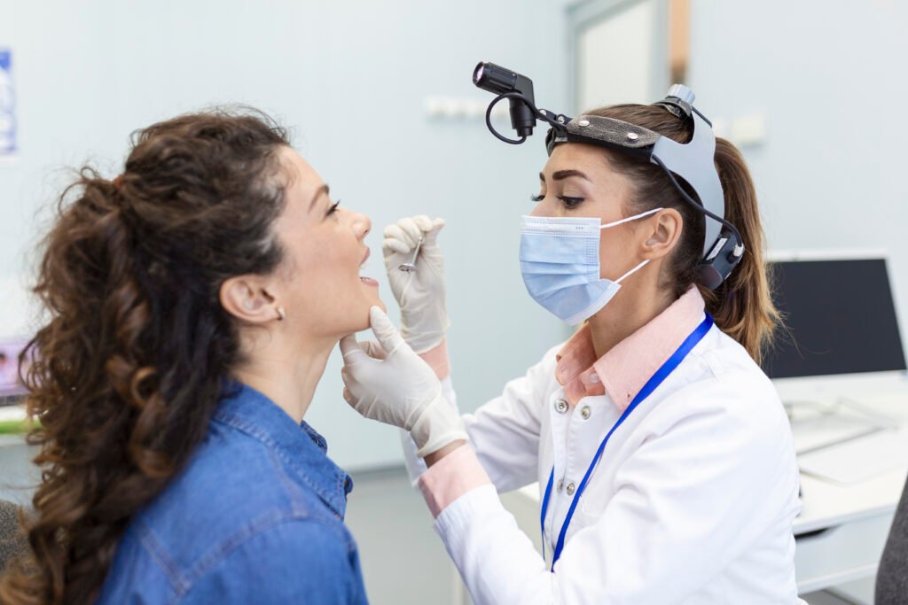 Dentist examining patient using dental headlight during oral checkup