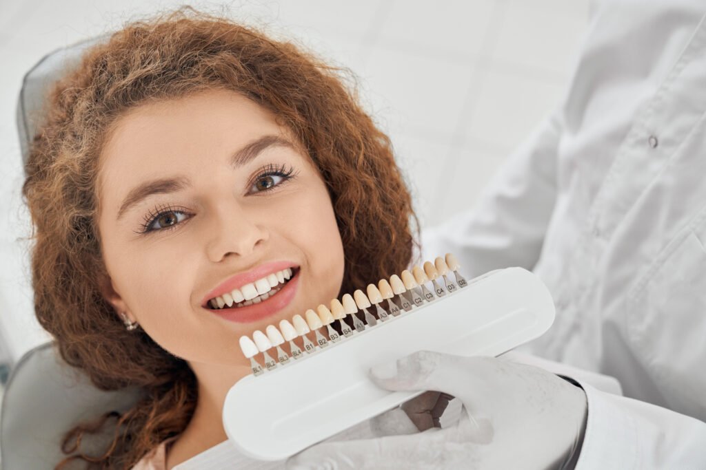 Patient smiling while dentist matches tooth shade for cosmetic dental treatment